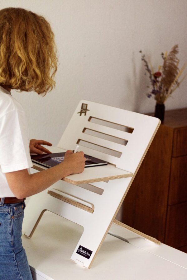 A woman using a modern adjustable standing desk at home, promoting ergonomic workspace solutions.