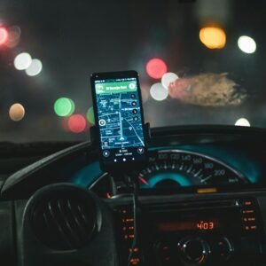 Close-up of a smartphone with map navigation in a car at night with bokeh effect.