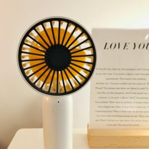 A sleek portable fan on a minimalist desk with decor, perfect for modern interior settings.