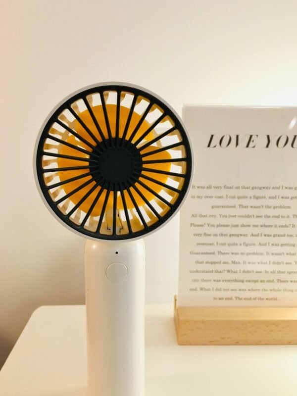 A sleek portable fan on a minimalist desk with decor, perfect for modern interior settings.