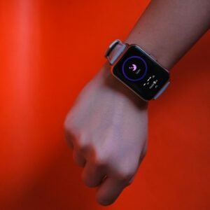 Fist wearing a smartwatch with fitness tracking display on a vibrant orange background.