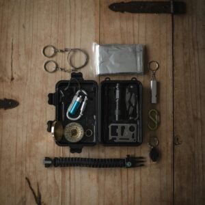 Top view of a compact survival kit with essential tools on a wooden surface.